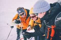 Tre personer i vinterklær planlegger en skitur i snødekte omgivelser.