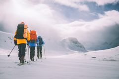 Personer på topptur i snødekte fjell under skyet himmel.