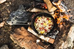 en stekepanne med pizza oppi, som står på et bål. bildet er tatt ovenfra