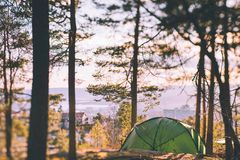 et grønt telt som står oppå en høyde. her er det utsikt ned til en by og vann mellom trærne