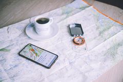 Et kart med en smarttelefon som viser en tur-app, en kopp kaffe og et kompass.