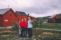 Vertskapet på Stranddalen smiler til kamera. I bakgrunnen er ei rødmalt hytte.