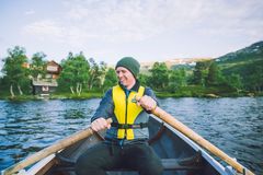 En person ror en båt på innsjøen ved Vangshaugen, med skog og hus i bakgrunnen.