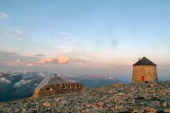To steinhytter, Skålabu og Skålatårnet, ligger på en steinete fjelltopp med fjellandskap i bakgrunnen.