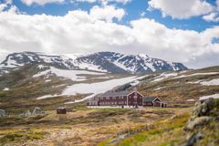 Bildet viser DNTs Glitterheim, en rød hytte omgitt av fjellandskap.
