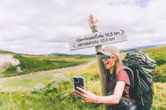 Kvinne tar en selfie foran et skilt som peker mot Gjevilvasshytta og Jøldalshytta i Trollheimen.
