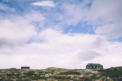 To hytter på et steinete landskap under en overskyet himmel på Hardangervidda.