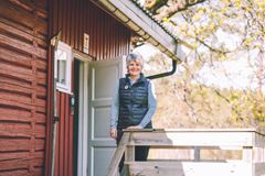 Kvinne står foran en rødmålt DNT-hytte.
