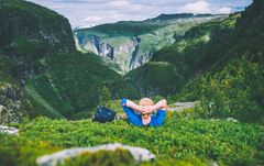 Person som hviler i gresset med vakker utsikt over Aurlandsdalen i bakgrunnen.