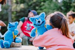 En jente klemmer en blå kosebamse. Hun sitter med ryggen til kamera.