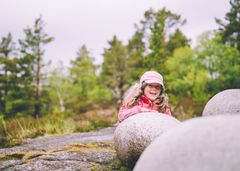 En jente ikledd rosa regntøy leker ute.