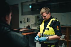 Toller med refleksvest og beskyttende hansker kontrollerer en reisendes bagasje på Oslo lufthavn.