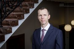 Portrett av etterretningssjef Erik Spradbrow foran en trappeoppgang. Spradbrow har på seg en dress med slips, og stirrer smilende inn mot kameraet.