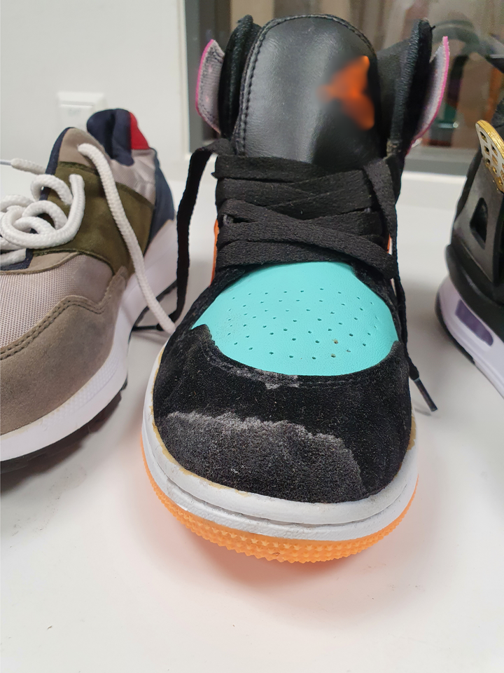 Sort%2C%20bl%E5%20og%20oransje%20joggesko%2C%20med%20%E9n%20sko%20p%E5%20hver%20side.%20Et%20lite%20oransje%20merke%20ved%20toppen%20av%20skoen.