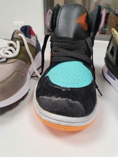 Sort, blå og oransje joggesko, med én sko på hver side. Et lite oransje merke ved toppen av skoen.