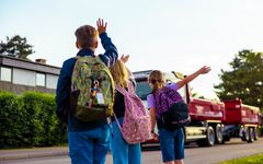 Skolebarn vinker til en lastebil som kjører forbi