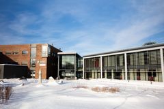 Universitetsbygg i vinterdrakt med blå himmel