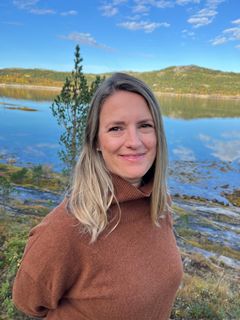 Bilde av kvinne som smiler foran et stort fjellvann
