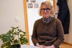 Bilde av voksen kvinne som sitter ved et bord med et blomster på inne på et kontor.