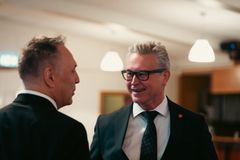 To menn i dress som snakker med hverandre, der den ene står mer ryggen til kamera. Foto