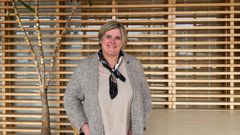 Bilde av kvinne i åpen ullkofte inne ved et bord