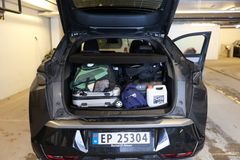 Mye bagasje bak i en bil med åpen bagasjeromsluke. Bagasjen er pakket på feil måte. Vi ser flere kofferter, ryggsekk og flere løse gjenstander.