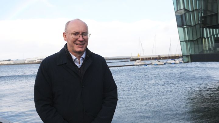 Voksen mann på kaia med en fjord i bakgrunnen. Det er overskyet.