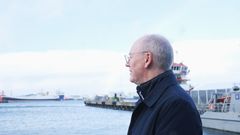 En voksen mann ser utover et havneområde, med skip i bakgrunnen