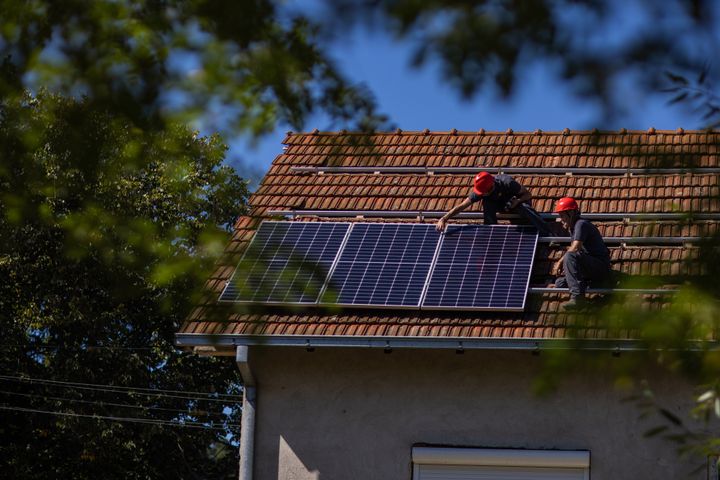 To menn monterer solceller på et hustak