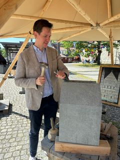 Ein mann i dress hugg stein med feisel og meisel