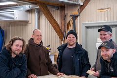 Fem smilende menn i et verksted.