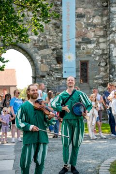 To menn i gjøglerkostyme holder hvert sitt instrument.