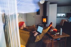 mann inne i en varm hytte med pc på fanget