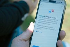 En hånd som holder en iPhone med menyen for nødanrop via satellitt synlig på skjermen
