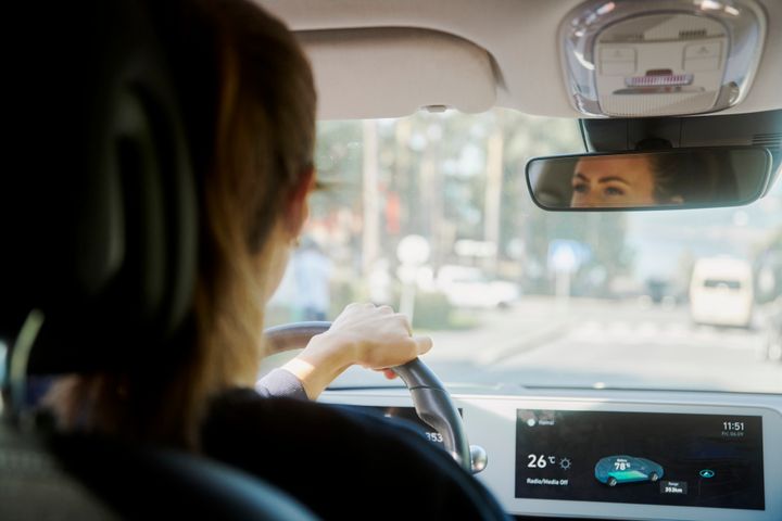 Kvinne som kjører bil i bytrafikk