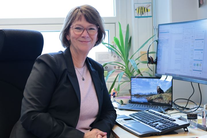 Fotografi av professor Lise Øvreås. Tatt på kontoret hvor Øvreås sitter på en kontorstol vedsiden av datamaskin.