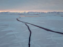 Bilde av Grønlandshavet med fjell i bakgrunnen og to store sprekker i isen