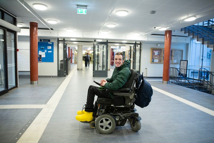 Bilde av ung mann i rullestol som smiler mot kamera
