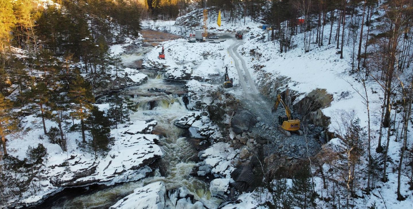 Anleggsområde, anleggsmaskiner, skog, vann. Foto.