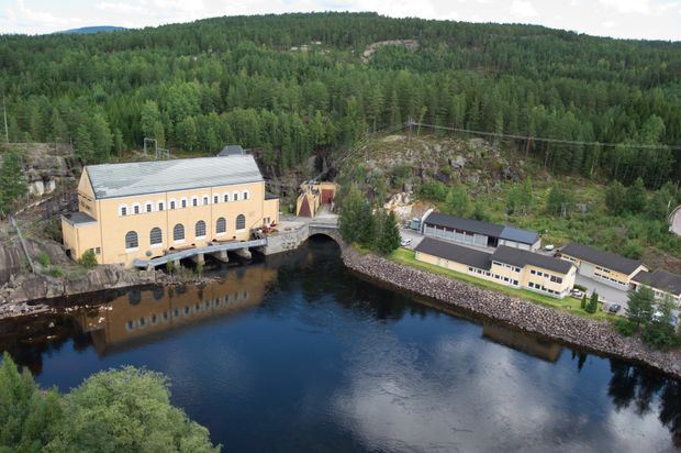 Kraftverk, vann, skog, kontorbygg, garasjebygg. Foto.