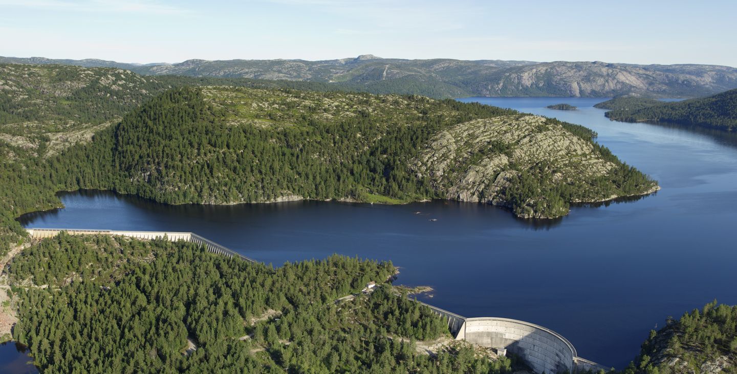 Dam, vann, fjell, skog, himmel. Foto.