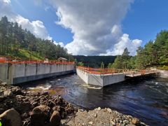 Anleggsområde, dam, vann, skog, himme. Foto.