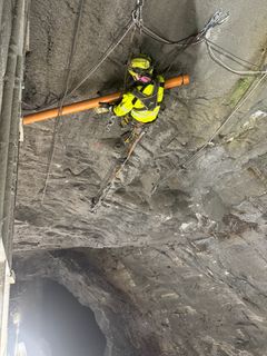 Mann som utfører fjellrensking inne i tunnel. Foto.