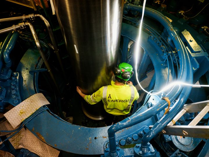 Mann i arbeidstøy som jobber inne i en kraftstasjon. Foto.