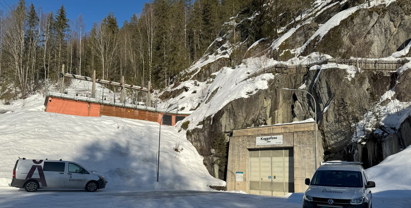 Kraftverk, strømlinjer, to biler, snø, skog, fjell, himmel. Foto.