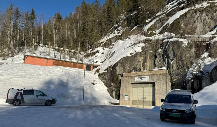 Kraftverk, strømlinjer, to biler, snø, skog, fjell, himmel. Foto.