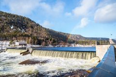 Elv, dam, gårdsbygning, fjell, skog, himmel, skyer, regnbue. Foto.