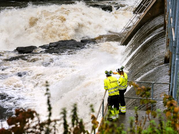 Kraftverkdam, vann, to personer i arbeidstøy. Foto.
