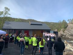 Kraftverk, himmel, skog, kor på scene, publikum. Foto.
