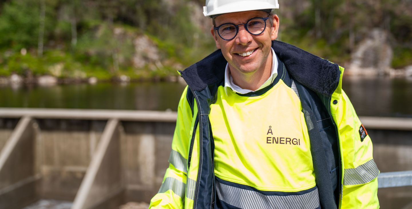 Kraftverk, dam, vann, mann med vernetøy og hjelm. Foto.